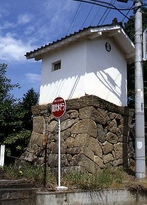 石垣の上に作られている白い塗り壁の「朝穂堰水配役人詰所文庫」の建物の写真