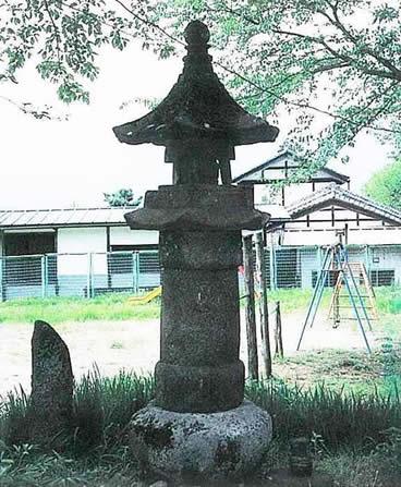 石の周りに苔が生えており、丸い石の上に置かれている古く趣のある宝積寺石幢の写真
