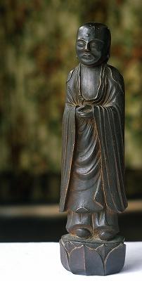 蓮の花の上に立っており、半眼(はんがん)で、優しい表情を浮かべている木喰仏(聖観音像)の写真
