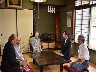山寺 あや子さんのご自宅にて、椅子に座っている山寺 あや子さんとご家族、市長と関係者が応接間の机の周りに座って、一緒に写っている写真