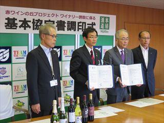 市長と関係者が調印書をもち並んでいる写真