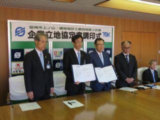 協定書を持つ市長と男性、その横に並ぶ関係者の写真