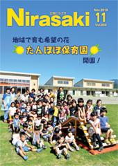 奥には保育園の建物が立っていて、手前の芝生に保育園児たちや保育士たちが集まっている様子が写っている広報にらさき11月号表紙