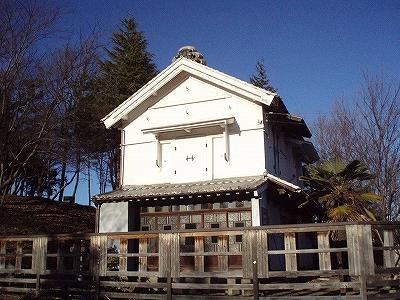 木の柵で囲まれている、白い塗り壁の韮崎宿豪商（富屋）の蔵屋敷の写真