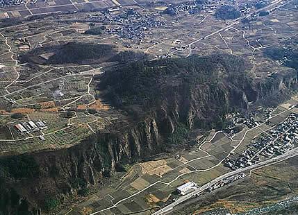 断崖絶壁の上の城跡が上空から写されている新府城跡の写真