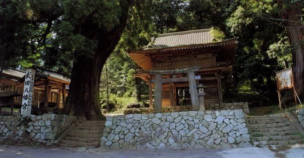 武田八幡宮の建物の前の石垣の上に立てられている趣のある石鳥居の写真