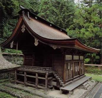 切妻照屋根で前の方の屋根が前に長く伸びた形の武田八幡宮本殿を横から写している写真