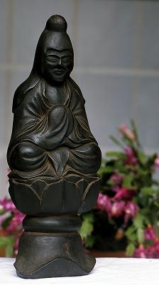 蓮の花の上に座っており、優しい表情の木彫像の木喰仏（岩船地蔵像）の写真