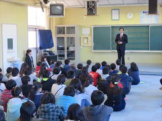 甘利小学校訪問し、着席する生徒の前で話をする市長の写真