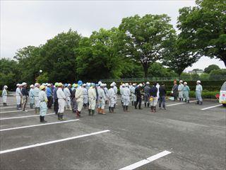 公園の駐車場に、地域ボランティア活動に参加される方々が集まって、整列している様子の写真