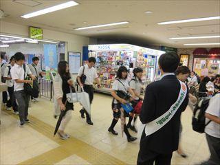 韮崎駅でタスキをかけている男性が、ホームから出て来た通行人に挨拶をしている様子の写真