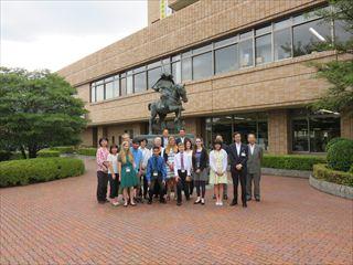 武田信義の銅像前で、ホームステイにやって来た6人の学生と関係者、市長が一緒に写っている写真