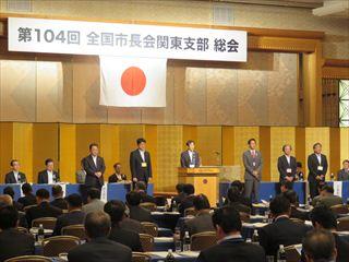 「全国市長会関東支部 総会」の会場で、市長が新任市長を代表して壇上にて、挨拶をしている様子の写真