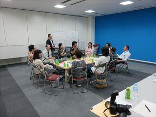 「まちづくりミーティング」の参加者が丸い円になって座っており、活発な意見交換がされている様子の写真