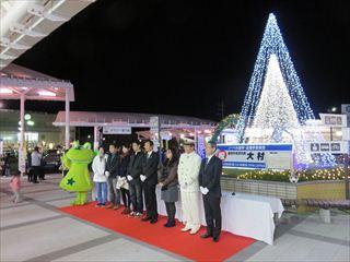 韮崎駅前イルミネーション点灯式で、ニーラーや関係者、市長がツリーの前に並んでいる写真