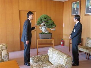 盆栽の前に立ち市長と話をしている秋山 実さんの写真