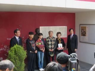 韮崎大村美術館の来館者10万人達成記念セレモニーで、10万人目のお客様が市長や関係者と並ぶ写真