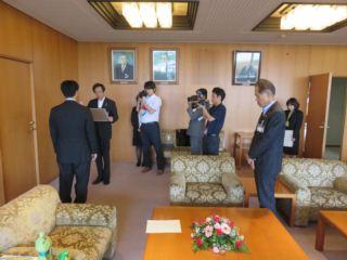 応接室にて加賀美 孝久さんが市長に表彰を受けており、その様子をカメラで撮影している様子の写真