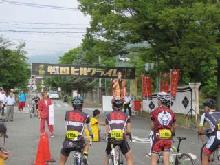 4名のヘルメットを被った参加者が自転車に乗って出発しようとしている写真