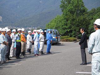 作業着に、ヘルメットを被ったボランティアの方々の前で、話をする市長の写真