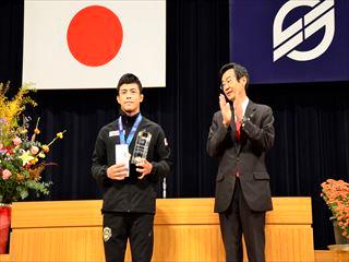 ジャージ姿の文田健一郎選手と、その横で拍手をする市長の写真