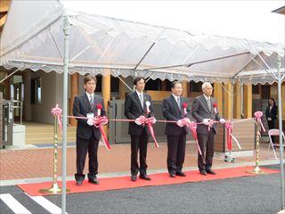 すずらん保育園竣工式で市長と関係者が、テントのなかで、紅白のテープカットをしようとしている様子の写真