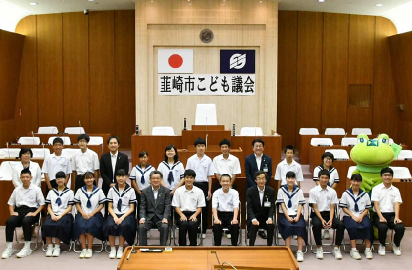 韮崎市こども議会で、横2列に並ぶ中学生の男女と関係者の集合写真