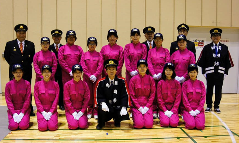 ピンク色の消防服を着ている韮崎市女性消防協力隊の皆さんと、市長と関係者の皆さんが一緒に写っている集合写真