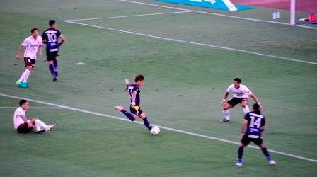 青いユニフォームを着た選手がゴール前でゴールを決めようと片足を振り上げている瞬間の写真