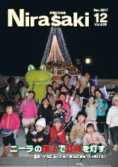夜空に光るクリスマスツリーの前で防寒服を着た子供たちとニーラの着ぐるみが並んでいる姿が写っている広報にらさき12月号表紙