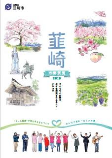わにつかの桜、平和観音、新府桃源郷のモモ、武田八幡宮、ブドウ園のイラストと市民の方々が笑顔で写っている市勢要覧2019の表紙