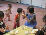 エプロンを着た女性が、スプーンで男の子にご飯を食べさせている写真